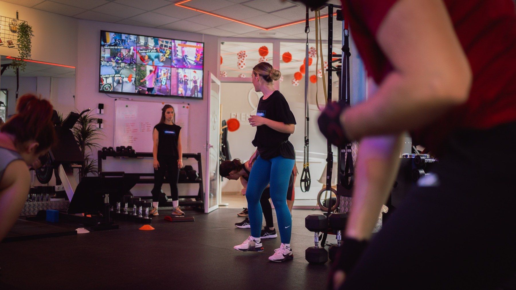 Grupo reducido entrenando en la sala de PlenaForma, con la pantalla de la sesión al fondo