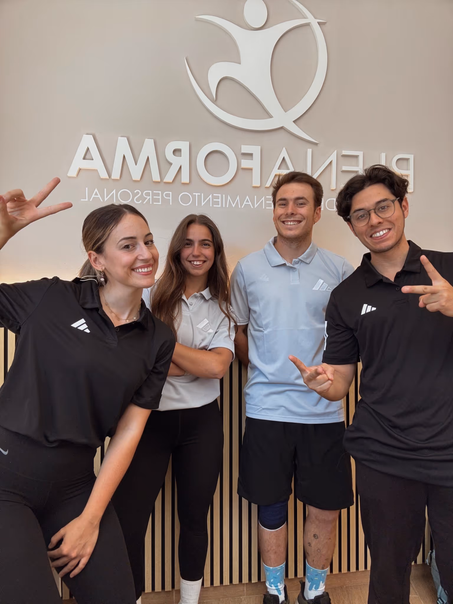 Los cuatro entrenadores de PlenaForma en la recepción del centro, bajo el rótulo